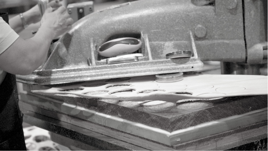 A clicker press cutting shapes from a sheet of leather