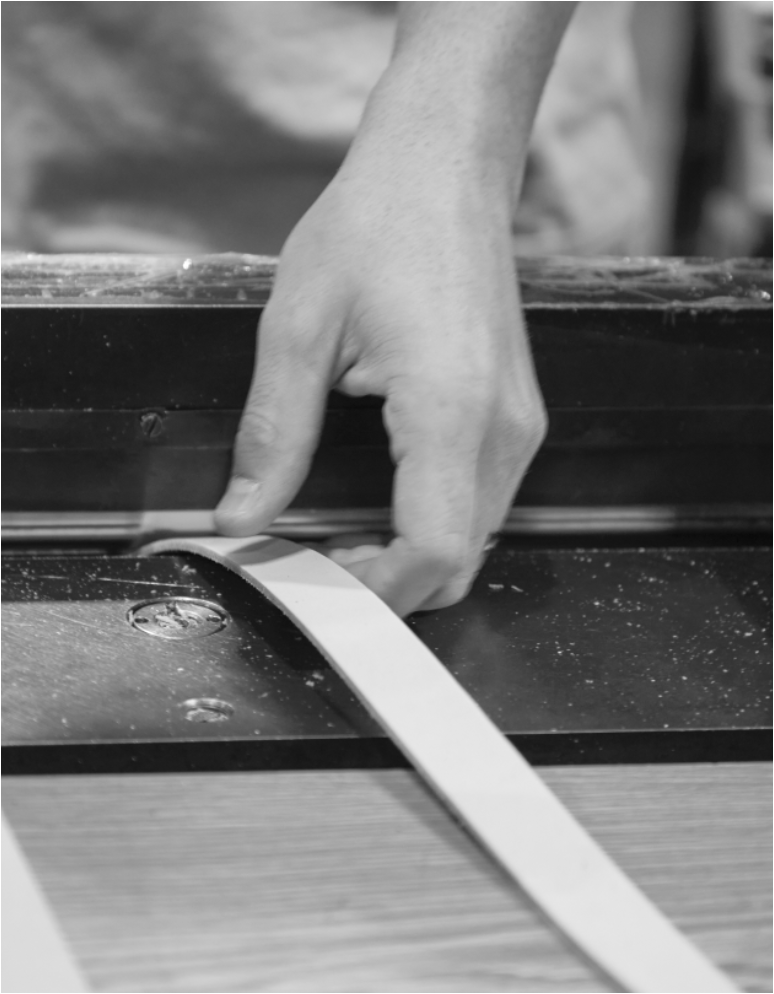 Hands guiding a leather strap through a cutting tool
